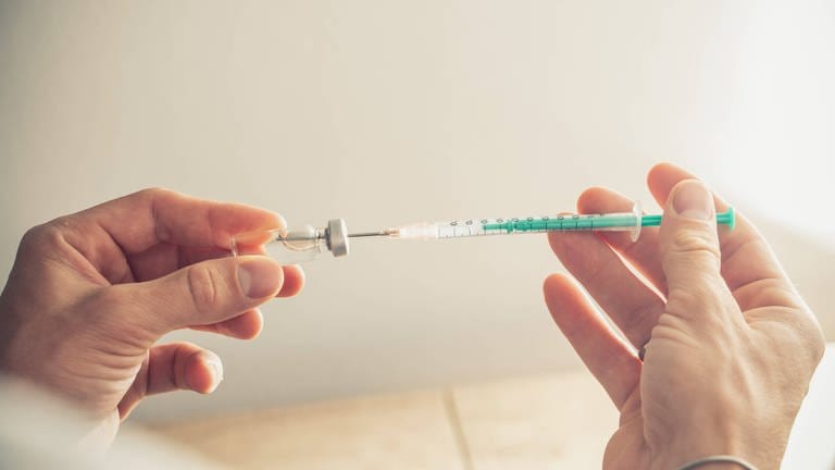 Das Bild zeigt, wie ein Impfstoffe mit einer Spritze aufgezogen wird. (Foto: IMAGO, Bihlmayerfotografie)