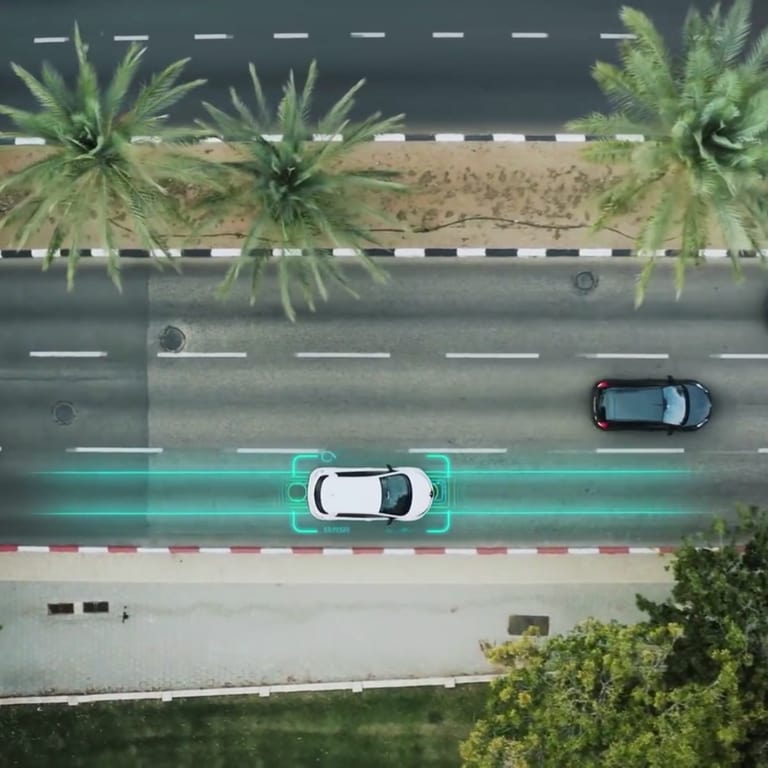 Eine dreispurige Straße, auf der drei Autos fahren. Unter einem Autos sind mit leuchtenden, blauen Linien die unter der Straße liegenden Magnetspulen dargestellt, die das Auto auf der rechten Spur laden. 