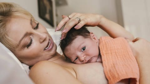 Ein Neugeborenes Baby liegt auf dem Bauch der Mutter mit engen Hautkontakt. (Foto: IMAGO, /Westend61)