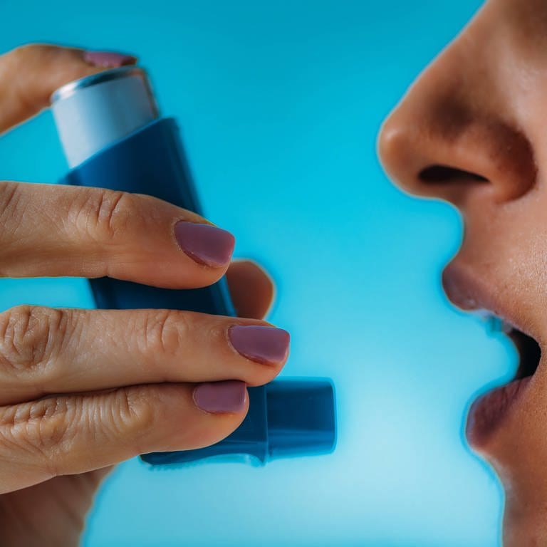 Frau mit Asthma nutzt einen Inhalator
