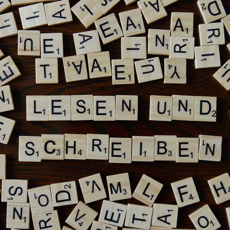 Das Bild zeigt die Wörter "Lesen" und "Schreiben" gelegt aus kleinen Holzbuchstaben. (Foto: IMAGO, Joko)
