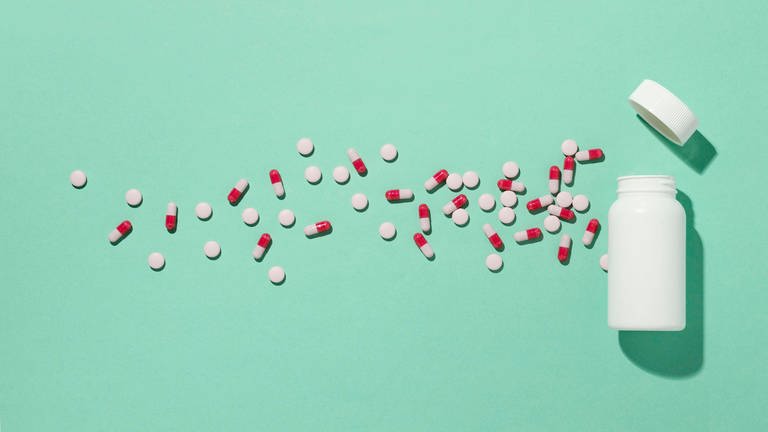 Das Bild zeigt viele Pillen neben einer Pillendose verteilt. (Foto: IMAGO, imagebroker)