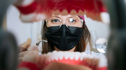 Das Bild zeigt eine Zahnärztin, die in einen Mund schaut.