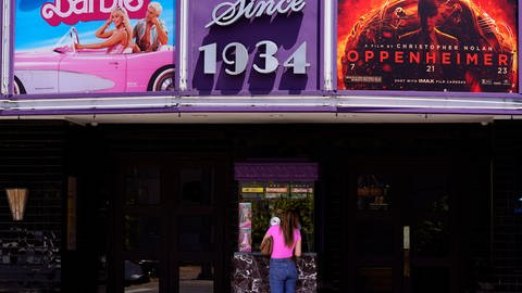 Eine Besucherin kauft eine Kinokarte unter einem Zelt auf dem Plakate zu den Filmen «Barbie» und «Oppenheimer» im Los Feliz Theatre ausgestellt sind.