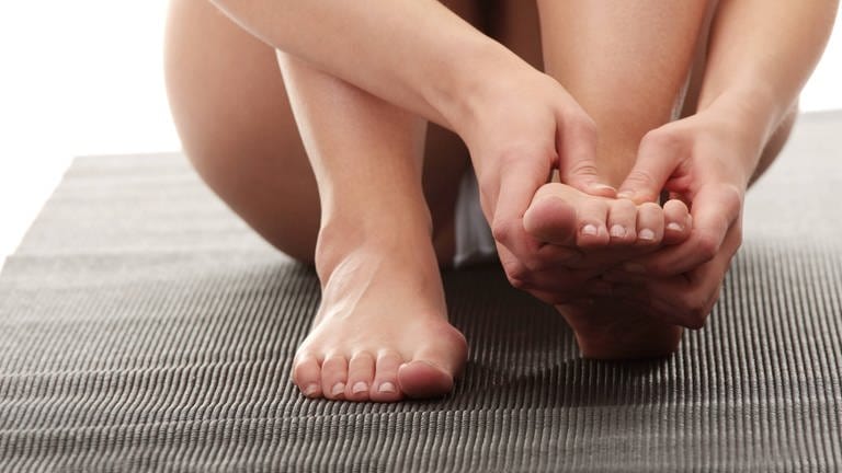 Rheumatische Erkrankungen treffen nicht nur ältere Menschen. Junge Frau mit schmerzenden Füßen.