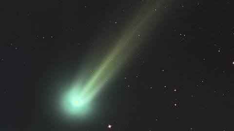 Ein Komet mit grünem Kopf und gelblichem Schweif. (Foto: dpa Bildfunk, IMAGO / StockTrek Images)
