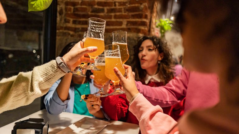Freunde stoßen mit ihren alkoholischen Getränken in einer Bar an. (Foto: IMAGO, IMAGO / Westend61)
