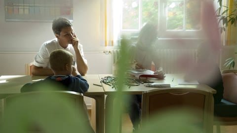 Das Bild zeigt eine Aufnahme aus der Kinder- und Jugendpsychiatrie Uchtspringe. Eine Therapeutin macht mit Kindern eine Maltherapie.