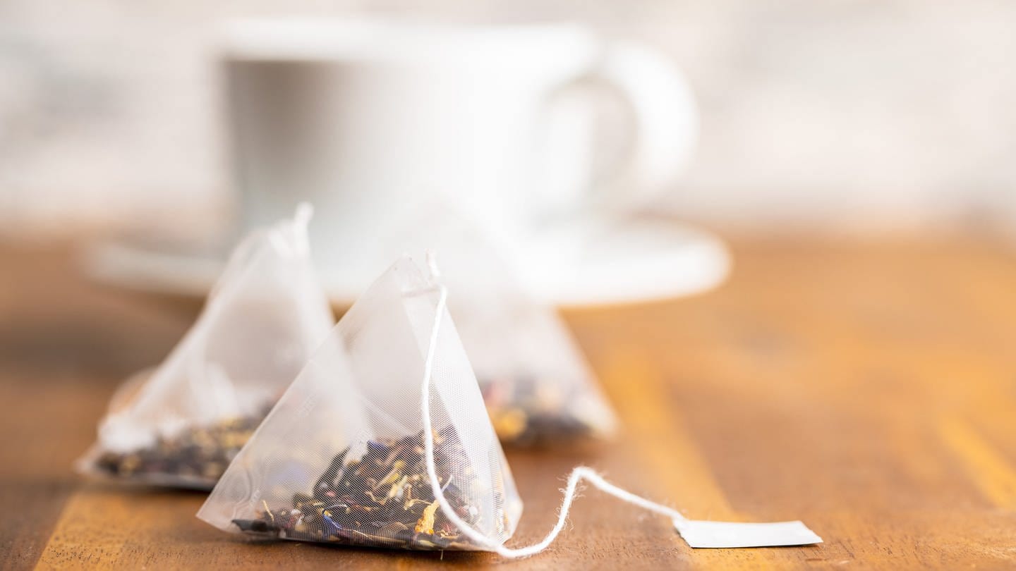 Teebeutel liegen vor einer Teetasse: Seit Jahren wird Tee verstärkt in pyramidenförmigen Kunststoffbeuteln angeboten. Teebeutel wie früher aus einfacher Zellulose, also Papierfasern, werden weniger. (Foto: picture-alliance / Reportdienste, picture alliance / Zoonar | JIRI HERA)