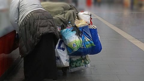 Eine obdachlose Person befindet sich mit ihrem gesamten Besitz in einem öffentlichen Gebäude.
