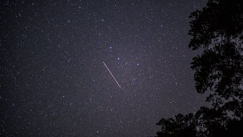 Ein Satellit ist sichtbar am Nachthimmel durch Langzeitbelichtung.