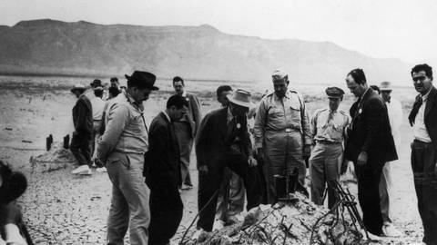 Mitwirkende des Manhattan-Projekts, darunter Dr. Robert J. Oppenheimer (Mann mit weißem Hut) und neben ihm General Leslie Groves, inspizieren die Detonationsstelle des Trinity-Atombombentests. (Foto: IMAGO, IMAGO/Pond5 Images)