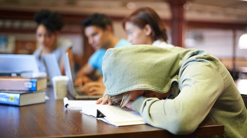 Ein Junge schläft in der Schule mit dem Kopf auf den Tisch gelegt, tags: innere Uhr, Bildschirmnutzung, Schlafenszeit (Foto: IMAGO, Zoonar)
