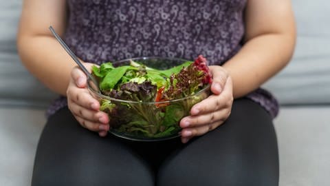Schüssel Salat auf dem Schoß einer Frau, tags: Abnehmspritze, Abnehm-Medikament, Geschichte