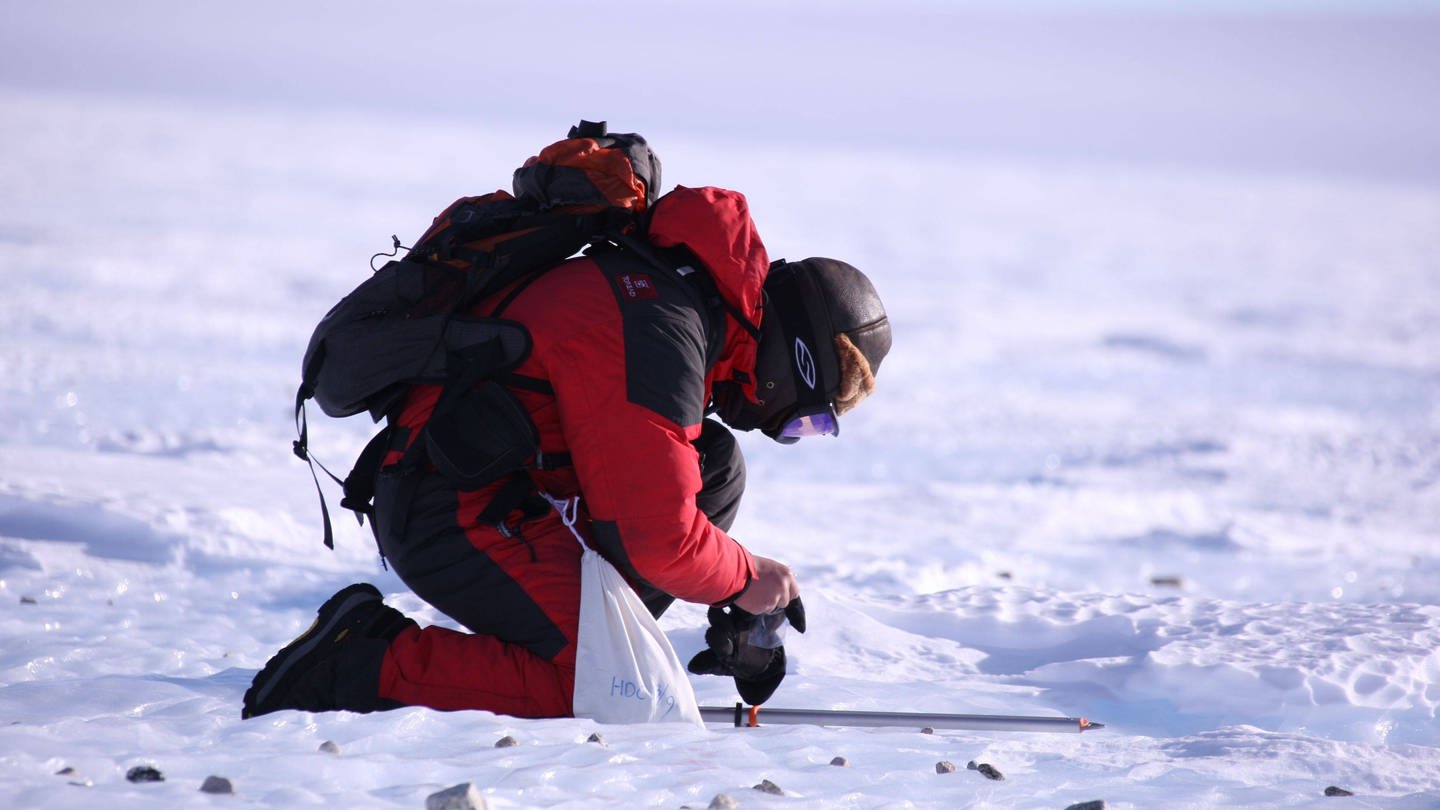 Ein Forscher kniet auf dem Eis. (Foto: IMAGO, IMAGO / Xinhua)