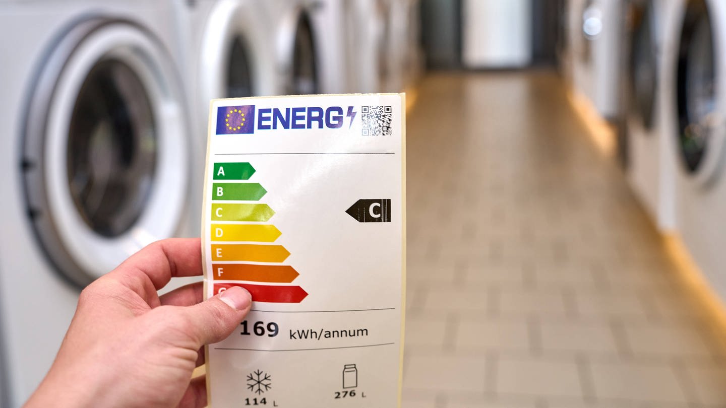 Energieeffizienz-Label vor einem Gang von Waschmaschinen. (Foto: IMAGO, IMAGO / Bihlmayerfotografie)