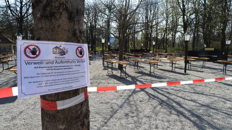 Ein Schild mit der Aufschrift "Verweil- und Aufenthalts Verbot" hängt an einem Baum am Biergarten am Aumeister im Englischen Garten, München. (Foto: dpa)