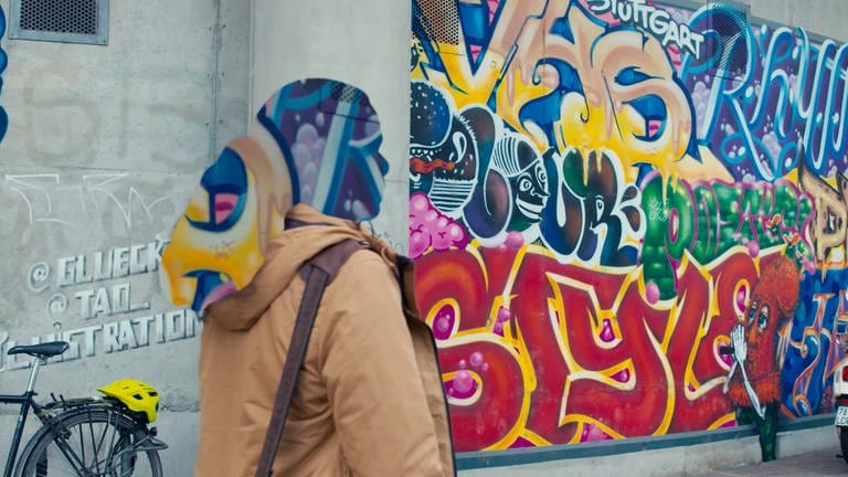 Frau läuft an einem Graffiti vorbei. Sie ist anonymisiert. (Foto: SWR)