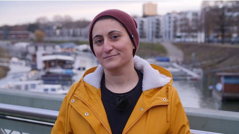 Porträt: Junge türkischstämmige Frau mit Mütze und gelbem Regenmantel