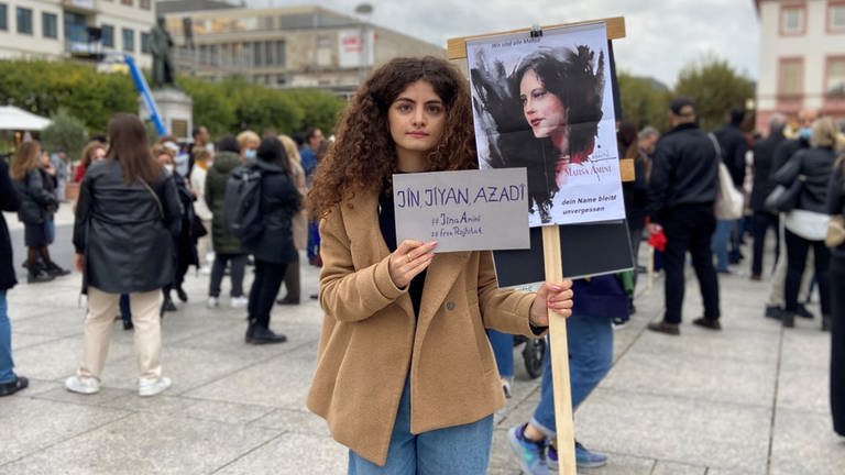 Eine junge Frau hält in Mainz bei einer Demo für Freiheit im Iran zwei Schilder in den Händen. (Foto: SWR, Damaris Diener)