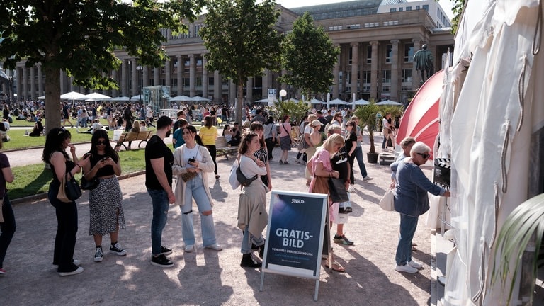 Besucher:innen stehen in der Festivalmeile Schlage für die Fotobox. (Foto: SWR, Markus Palmer) Besucher:innen stehen in der Festivalmeile Schlage für die Fotobox.