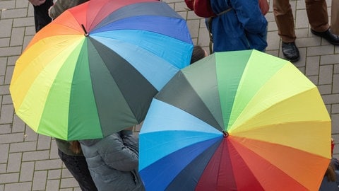 Aufgespannte Regenschirme in Regenbogenfarben. Ab Samstagabend soll in Rheinland-Pfalz Regen fallen.