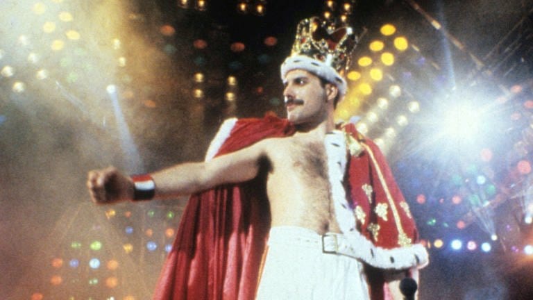 Freddie Mercury steht bei seinem Konzert in Mannheim 1986 auf der Bühne und trägt eine Krone und einen königlichen Umhang (Foto: picture-alliance / Reportdienste, Photoshot)