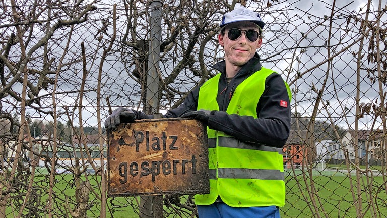 Mit Sonnenbrille, Mütze, gelber Weste und Handschuhen hat Jan in der Donau ein Metallschild aus der Donau gefischt. (Foto: SWR) Mit Sonnenbrille, Mütze, gelber Weste und Handschuhen hat Jan in der Donau ein Metallschild aus der Donau gefischt.