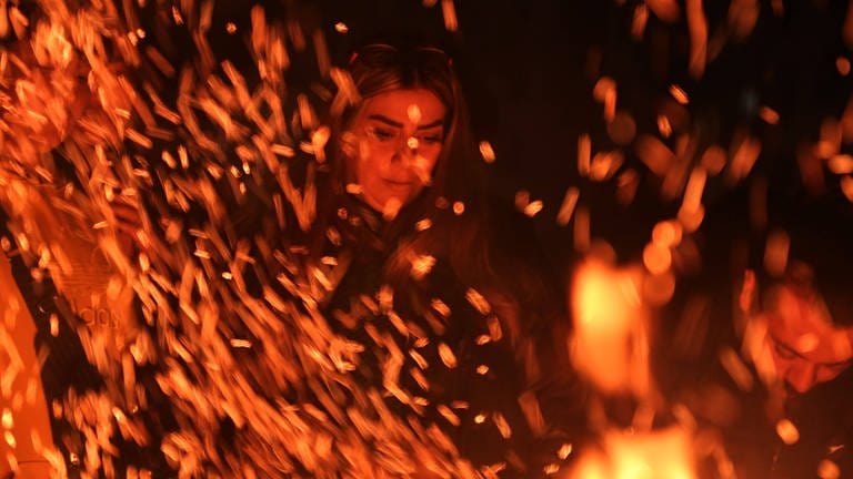 13. März: Eine iranische Frau beobachtet das lodernde Lagerfeuer des traditionellen Feuerfestes "Chaharshanbeh Soori". Ein iranisches Fest, das seit über dreitausend Jahren - am letzten Mittwoch vor dem Frühlingsfeiertag "Nowruz" - gefeiert wird. (Foto: IMAGO, IMAGO/ZUMA Wire)