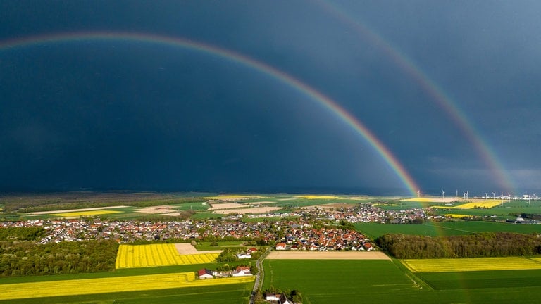 25. April: Ein eindrucksvoller, doppelter Regenbogen spannt sich über die Ortschaft Büren-Steinhausen im Kreis Paderborn, während dunkle Gewitterwolken den Himmel dramatisch färben – festgehalten aus der Luft mit einer Drohne. (Foto: picture-alliance / Reportdienste, dpa Bildfunk, Christoph Reichwein) 25. April: Ein eindrucksvoller, doppelter Regenbogen spannt sich über die Ortschaft Büren-Steinhausen im Kreis Paderborn, während dunkle Gewitterwolken den Himmel dramatisch färben – festgehalten aus der Luft mit einer Drohne.