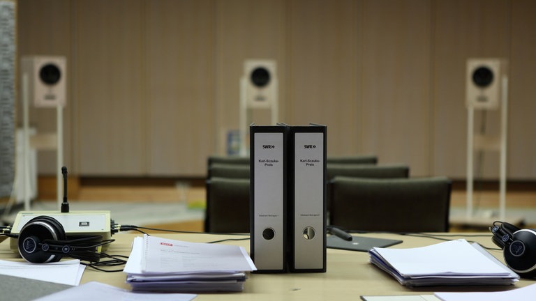 Tisch mit zwei Aktenordnern und drei Lausprechern im Hintergrund (Foto: SWR, Frank Halbig)