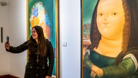 Eine Frau macht ein Selfie vor einer Karikatur der Mona Lisa  (Foto: IMAGO, imago images/VWPics)