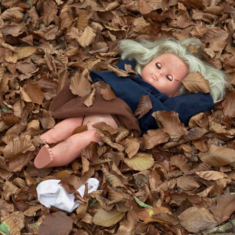 Symbolfoto sexueller Missbrauch, Puppe mit hochgezogenem Rock und entblößtem Unterleib liegt im Laub (Foto: picture-alliance / Reportdienste,  imageBROKER | Olaf Heil)