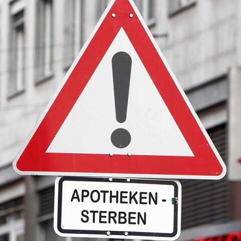 Apothekensterben in Deutschland: Verkehrszeichen Achtung Gefahr mit Zusatzschild Apotheken-Sterben vor dem Logo einer Apotheke in Frankfurt, Hessen, Deutschland *** (Foto: IMAGO, Foto: Ralph Peters)
