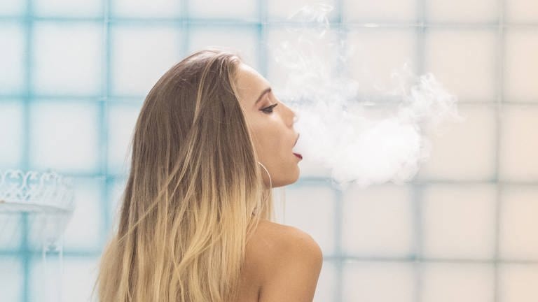 Eine Frau sitzt auf der Badewanne und raucht eine Wasserpfeife (Foto: IMAGO, IMAGO / Addictive Stock)