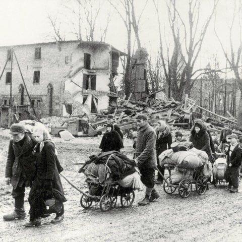 Flucht aus den deutschen Ostgebieten vor den vorrückenden Truppen der Roten Armee im Frühjahr 1945: eine Gruppe von Flüchtlingen mit Handwagen in einer zerstörten Ortschaft in Ostpreußen (Foto: picture-alliance / Reportdienste, picture alliance / akg-images | akg-images)