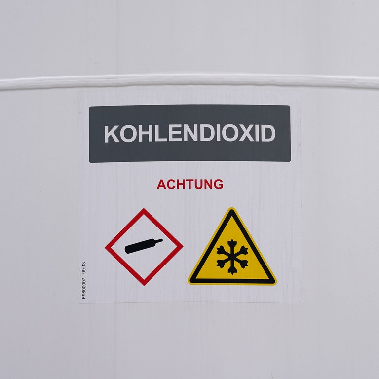 "Kohlendioxid" steht auf einem Tank der neuen Power-to-Liquid-Demonstrationsanlage auf dem Gelände der Raffinerie H&R Ölwerke Schindler GmbH im Hafen. Mit der Anlage sollen aus natürlichen Wasserstoffen und Kohlenstoffdioxid (CO2) nachhaltige Treibstoffe für den Straßen- und Luftverkehr, sogenannte E-Fuels, hergestellt werden. (Foto: picture-alliance / Reportdienste, picture alliance/dpa | Marcus Brandt)