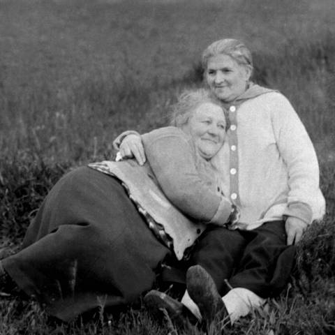 Zwei Frauen kuscheln um 1940 auf einer Wiese: Frauenliebende Frauen waren in Deutschland lange Zeit in der Öffentlichkeit nicht präsent, waren quasi unsichtbar. Sie wurden entweder gesellschaftlich ignoriert, angefeindet oder gar verfolgt. (Foto: IMAGO, IMAGO / imagebroker)