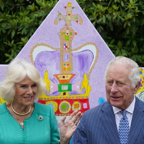 König Charles und Camilla sitzen auf einer bunten von Schülern entworfenen Bank (Foto: dpa Bildfunk, Picture Alliance)