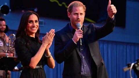 Prinz Harry von Großbritannien und seine Frau, Meghan, Herzogin von Sussex, stehen während der Invictus Games in Düsseldorf auf der Bühne. Beide nahmen an einem «Friends & Family»-Abendtermin der Spiele teil. Sie klatscht in die Hände und lacht, er zeigt mit dem Zeigefinger nach vorn. (Foto: dpa Bildfunk, Picture Alliance)