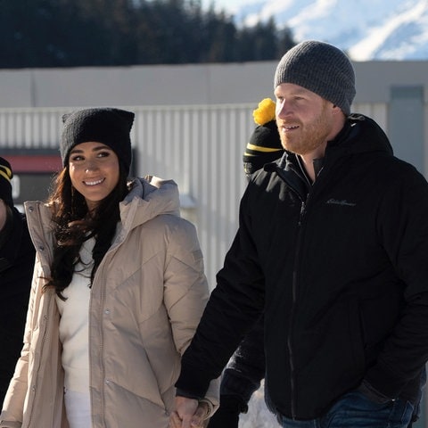 Prinz Harry und Herzogin Meghan auf einer Ski-Piste in Kanada. Sie trägt eine schwarze Mütze, unter ihrem beige-farbenen Mantel ist sie komplett in weiß gekleidet. Er trägt eine graue Mütze, eine schwarze Jacke und blaue Jeans. Die Sussexes besuchen das Traineingslager der Incivtus Games. (Foto: picture-alliance / Reportdienste, picture alliance/dpa/The Canadian Press via AP | Ethan Cairns)