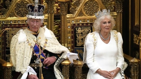 König Charles und seine Frau Königin Camilla sitzen auf einem prachtvollen Thron mit Kronen und Umhang und schicken Gewändern. Er wartet darauf seine Rede zur Parlamentseröffnung im House of Lords zu lesen, sie nahm soeben Platz neben ihm. (Foto: dpa Bildfunk, picture alliance/dpa/PA Wire | Kirsty Wigglesworth) König Charles und seine Frau Königin Camilla sitzen auf einem prachtvollen Thron mit Kronen und Umhang und schicken Gewändern. Er wartet darauf seine Rede zur Parlamentseröffnung im House of Lords zu lesen, sie nahm soeben Platz neben ihm.