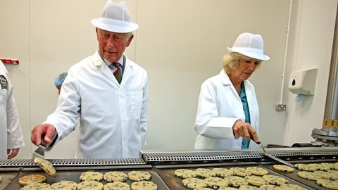 König Charles und Königin Camilla wenden walisische Kekse während ihres Rundgangs durch die Village Bakery in Wrexham. (Foto: picture-alliance / Reportdienste, picture alliance / empics | Peter Byrne) König Charles und Königin Camilla wenden walisische Kekse während ihres Rundgangs durch die Village Bakery in Wrexham.