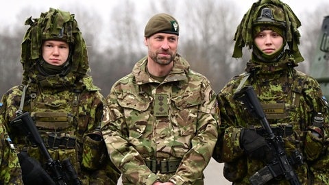 Prinz William steht in grüner Kampfuniform zwischen zwei Soldatinnen der estinschen Armee. (Foto: picture-alliance / Reportdienste, picture alliance/dpa/PA Wire | Victoria Jones) Prinz William steht in grüner Kampfuniform zwischen zwei Soldatinnen der estinschen Armee.