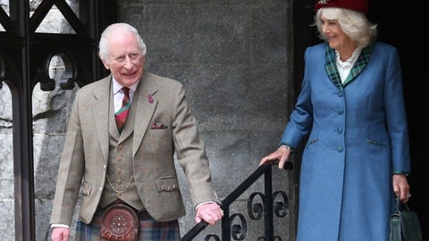 König Charles und Königin Camilla beim Gottesdienst zu ihrem 20. Hochzeitstag. Charles trägt ein braun-kariertes Sakko mit Weste und Schottenrock. Camilla trägt ein blaues Kleid mit rotem Hut. (Foto: picture-alliance / Reportdienste, picture alliance / empics | Peter Jolly/Scottish Daily Mail) König Charles und Königin Camilla beim Gottesdienst zu ihrem 20. Hochzeitstag. Charles trägt ein braun-kariertes Sakko mit Weste und Schottenrock. Camilla trägt ein blaues Kleid mit rotem Hut.