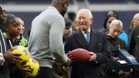 König Charles witzelt mit dem Football-Star Efe Obada rum und hält einen Football in der Hand. (Foto: picture-alliance / Reportdienste, picture alliance/dpa/Pool PA | Lucy North) König Charles witzelt mit dem Football-Star Efe Obada rum und hält einen Football in der Hand.