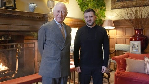 König Charles III. trifft den ukrainischen Präsidenten Wolodymyr Selenskyj auf dem britischen Landsitz Sandringham. Die beiden stehen vor einem Kamin aus Holz und lächeln in die Kamera. (Foto: picture-alliance / Reportdienste, picture alliance/dpa/PA Wire | Joe Giddens) König Charles III. trifft den ukrainischen Präsidenten Wolodymyr Selenskyj auf dem britischen Landsitz Sandringham. Die beiden stehen vor einem Kamin aus Holz und lächeln in die Kamera.