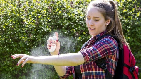 Junge Frau trägt Mückenschutz auf - das Spray hilft auch gegen Grasmilben (Foto: IMAGO, Jochen Tack)