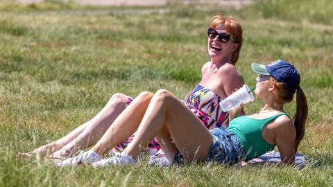 Entspannen im Sommer in der Sonne bei tollem Wetter: Zwei Frauen liegen auf einer Wiese (Foto: picture-alliance / Reportdienste, ZUMAPRESS.com | Alex Lentati)