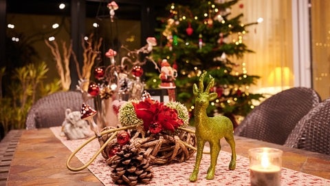Weihnachtsdeko auf Tisch mit Weihnachtsbaum im Hintergrund. (Foto: picture-alliance / Reportdienste, picture alliance/dpa | Annette Riedl)